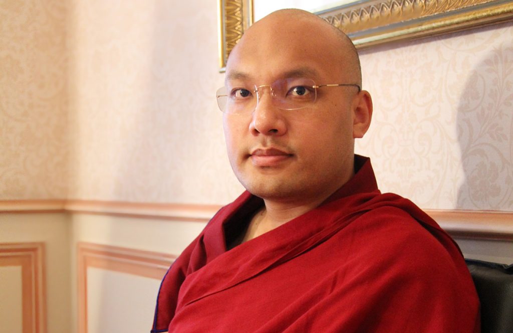 un portrait du 17 Karmapa, chef spiruule tibétain reconnu par le Dalaï Lama. Il porte sa robe rouge de moine et regarde l'appareil photo avec un regard proofnd et tendre.