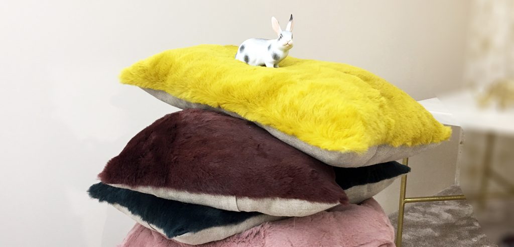 Un petit lapin en plastique est posé sur un epile de coussins très confortables