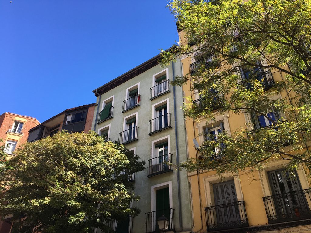 Dans une rue de ville, on voit le haut des immeubles colorés qui se détachent sur fond de ciel bleu.