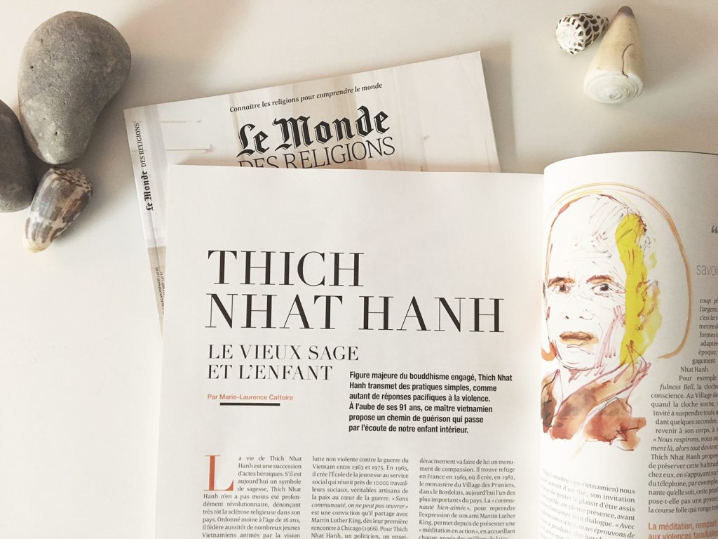 La revue le Monde des Religions est posée sur une table blanche et ouverte aux pages 81 et 82 où se trouve un portrait de Thich Nhat Hanh. Quelques coquillages et galets sont posés à côté du magazine.