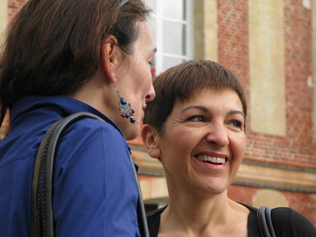 Deux femmes se parlent et sourient. On ne voit que leur visage. Elles ont l'air vraiment heureuses d'être ensemble.