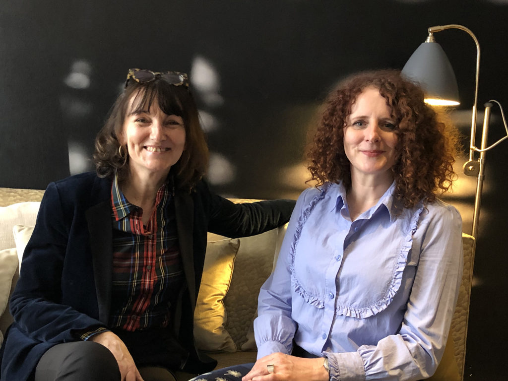 MarieLaurence Cattoire et Maggie O'Farrel sont assises côté à côte dnas le lobby d'un hôtel pariisen. Elles regardent l'objectif et sourient toutes les deux.