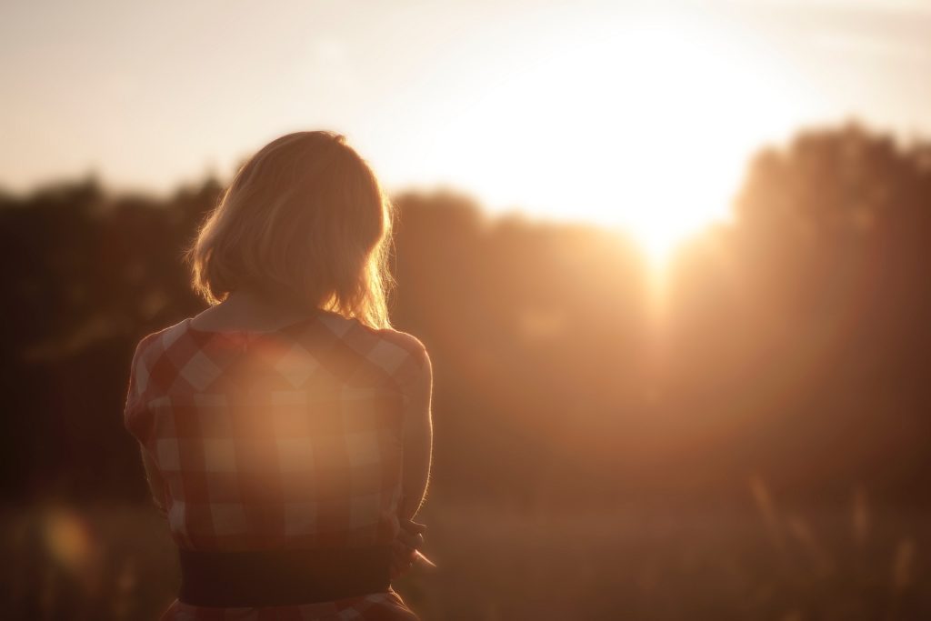 Une idée du merveilleux : Une femme de dos, regarde le soleil. Les couleurs osnt chaudes et réconfortantes