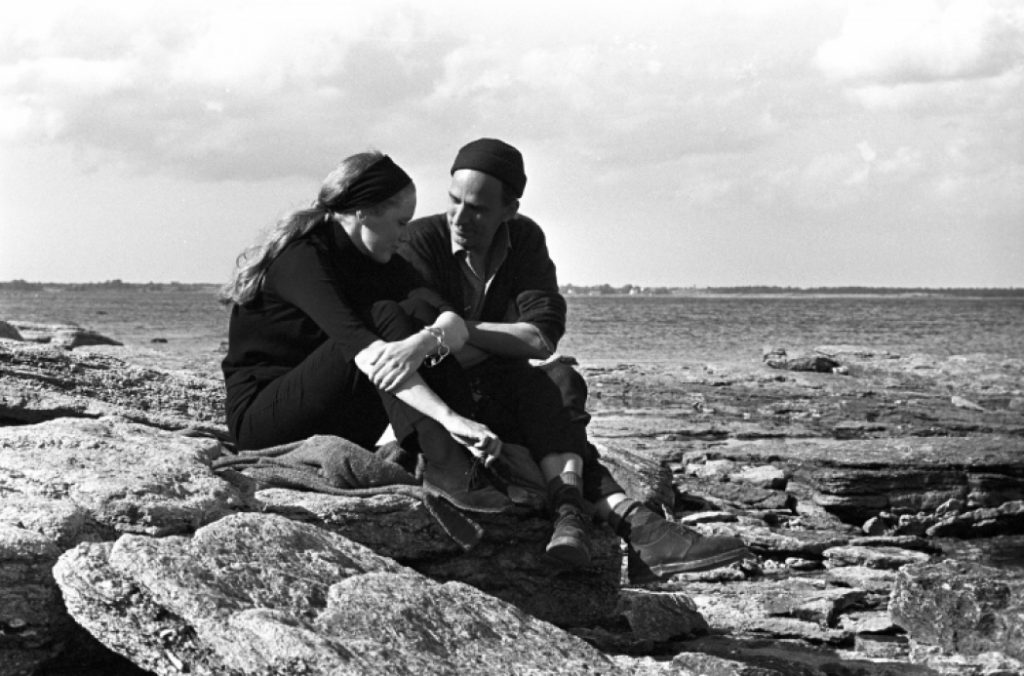 Liv Ullmann E INgmar Bergman assis cote a cote sur un rocher. La photo est en noir et blanc.