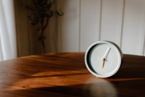 la magie du temps inutile symbolisée par un réveil matin posé sur un meuble en bois vernis devant un mur en lambris blanc