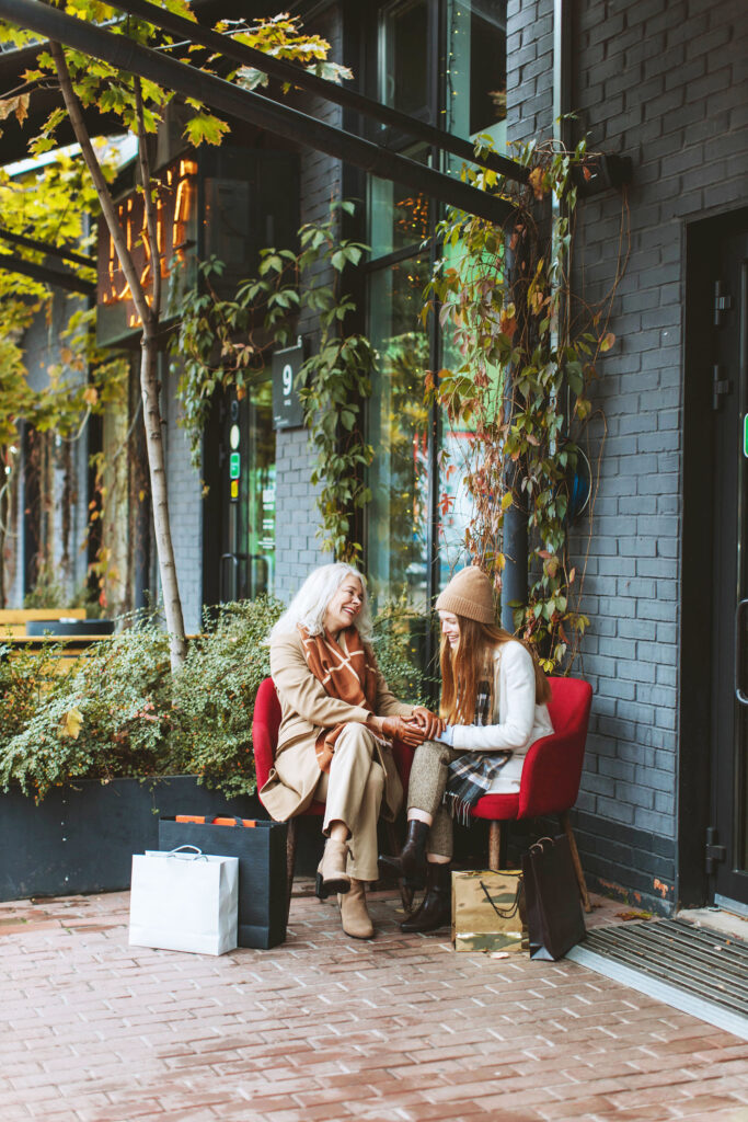 une grand mère et sa petit fille déjà femme discutent enesmble joyeusement. Elles sont assise sur de beaux fauteuils rouges