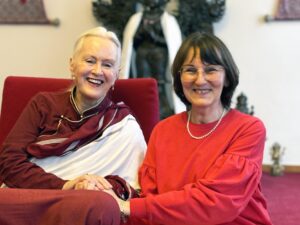 Lama Tsultrim Allione et Marie-Laurence Cattoire sont assises cote à cote. Lama tient la main de Marie-Laurence. Elles sourient à l'objectif